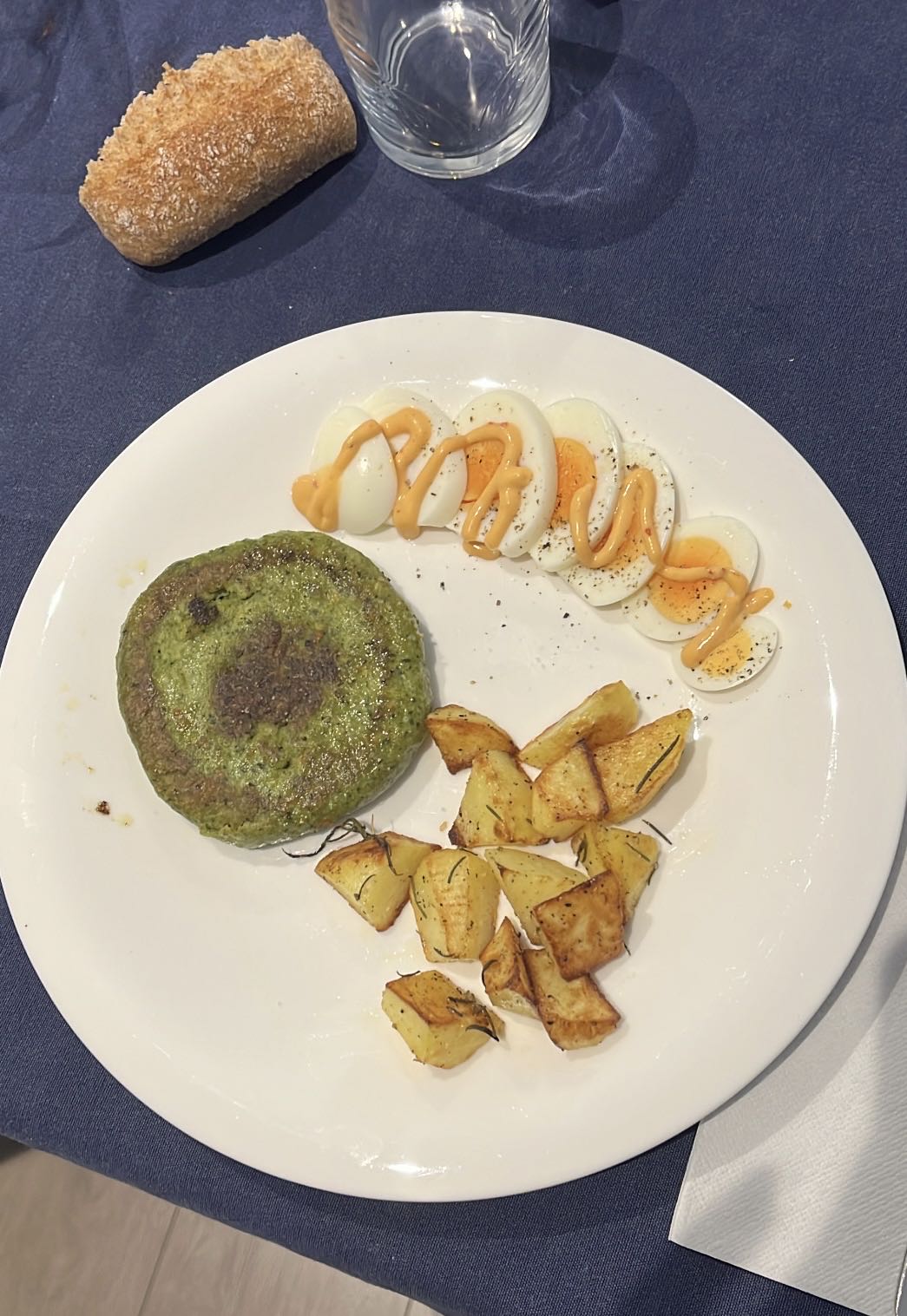 Hamburguesa de espinacas con patatas al horno, panecillo integral y huevo duro con salsa brava